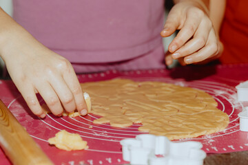 One girl bakes cookies, removing excess dough.