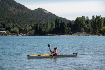 Young lady enjoying the summer while taking a kayak ride on the lake, Bariloche, Argentina.