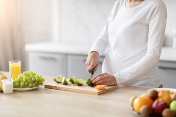 Pregnant woman slicing fruits on wooden board