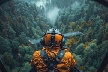An intense focus on the back of a helicopter pilot, clad in an orange suit, with the foggy forest below