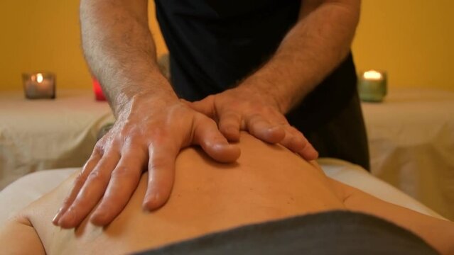A male masseur massages the muscles of the back 1
