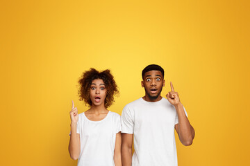 Stunned black man and woman pointing upward with opened mouths