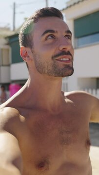 Vertical Video call of an Attractive young Caucasian smiling man takes a selfie to social media on a beach. He waves to the camera and blows kisses as he enjoys his time off during the summer holidays