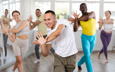 Positive Asian boy engaged in active dance together with other attendees of dancing courses