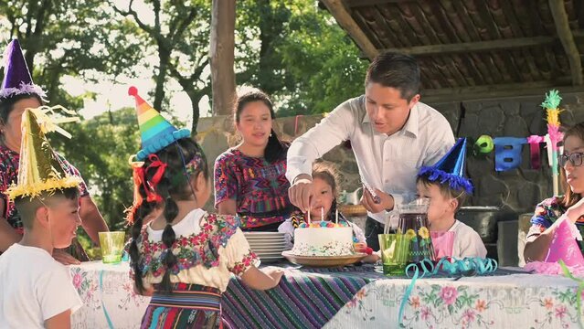 Latin family of the Mayan ethnic group, celebrates the birthday of their best son and everyone, together with a colorful cake, waits for the candles to be blown out.