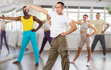 Positive Asian boy engaged in active dance together with other attendees of dancing courses