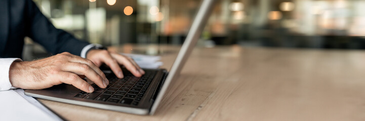 Closeup businessman using laptop, typing on keyboard