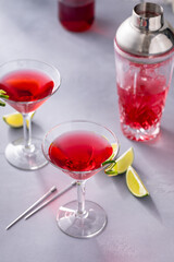Martini cocktail with cranberry juice garnished with lime twist