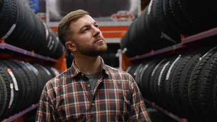 A man walking in a tire store and choose new tire for car