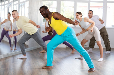 Happy African american man and group of international dancers training before big performance in...