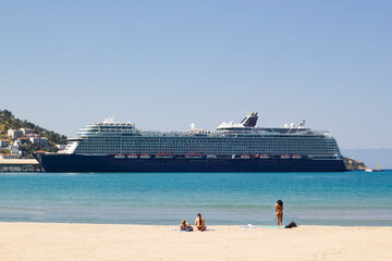 View from the beach of a very large tourist cruise ship tied up in the port
