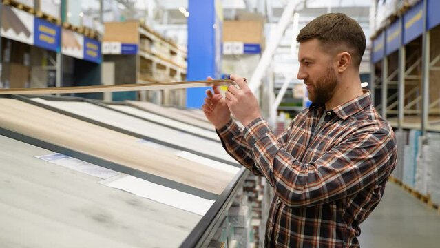A man choosing wood laminated flooring in shop