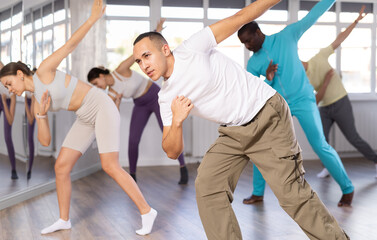European man conducts lesson for multinational people company, teaches men and women to move...