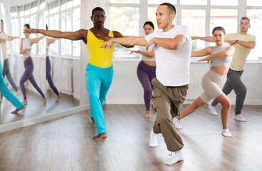 Slim young Asian man practicing active dance in training hall during dancing classes