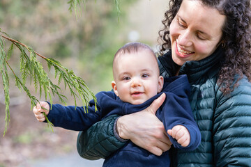 Caucasian Baby Boy and Mother in Forest playing with branches and trees.