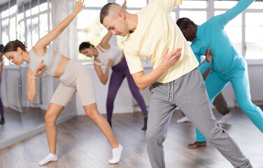 European man conducts lesson for multinational people company, teaches men and women to move...