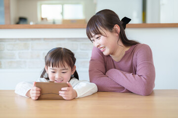 スマートフォンを使う親子　女の子とお母さん - obrazy, fototapety, plakaty