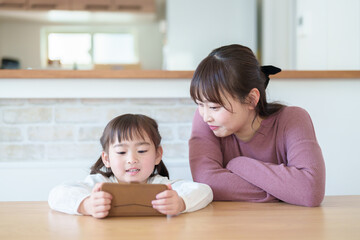 Obraz na płótnie Canvas スマートフォンを使う親子　女の子とお母さん