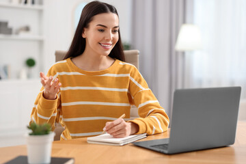 Young woman using video chat during webinar at table in room