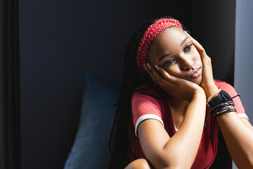 African American young woman sitting, looking thoughtful at home with copy space