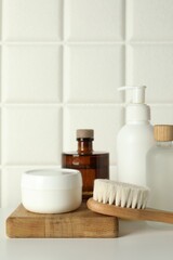 Fototapeta premium Bath accessories. Personal care products and wooden brush on white table near tiled wall