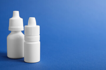 Bottles of medical drops on blue background, space for text