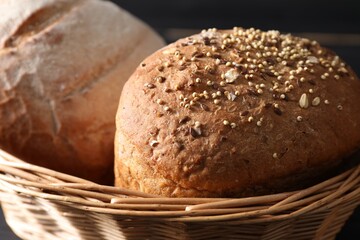 Wicker basket with fresh bread on dark background, closeup - obrazy, fototapety, plakaty