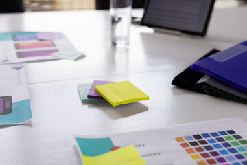 Colorful sticky notes and app design papers are lying on a table in a modern business office