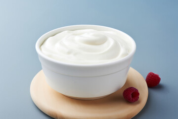 Obraz na płótnie Canvas Plain yogurt or Greek yogurt in a bowl served with fresh berries on light blue background
