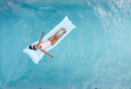 African American young girl floating on a water mat at home, wearing swimsuit, copy space