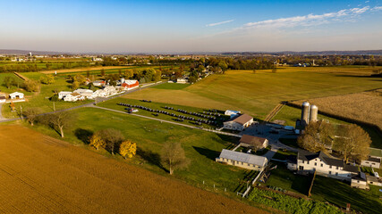 This aerial image displays the vast beauty of Amish farmland at dusk, with a serene sunset...
