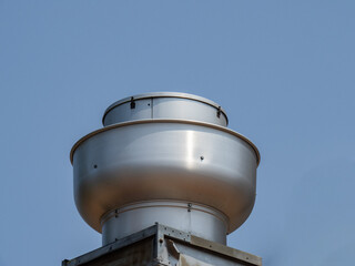 A round aluminum restaurant kitchen exhaust vent grease trap against a blue sky