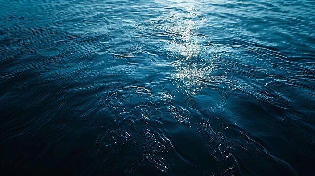 Glistening sunlight on deep blue ocean water surface under clear sky