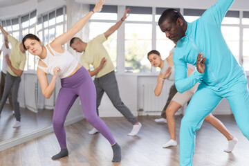 Happy African american man and group of international dancers training modern dance in modern dance...