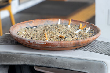 A bowl with sand for butts on a trash can on the street