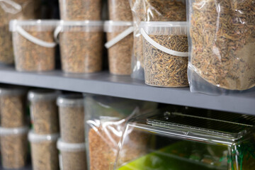 On shelf in pet store there are containers of various weights and capacities with dry food for...