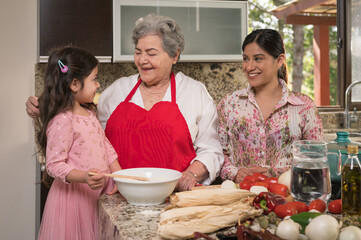 Grandmother and mother talk with their granddaughter and daughter, during the process of preparing...