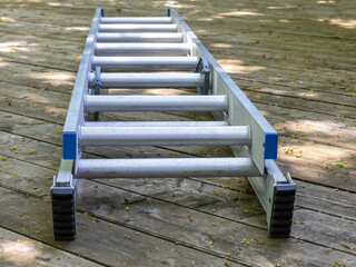 an aluminum extension ladder lying on a wooden deck