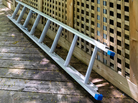 an aluminum extension ladder leaning against a wooden deck