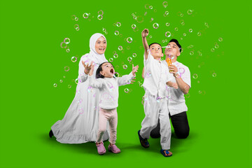 Young Muslim mother and father playing soap bubbles with their children