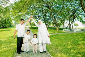 Happy Asian muslim family of four having fun together at park