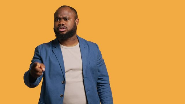 Angry african american man fighting with friend over debacle, isolated over studio background. Rude person in disagreement with mate, swearing and pointing finger, camera A