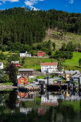 Fototapeta na wymiar Calm waters of Stangvikfjord reflect the quaint Kvanne village and ferry terminal under a blue summer sky, Møre og Romsdal, Norway