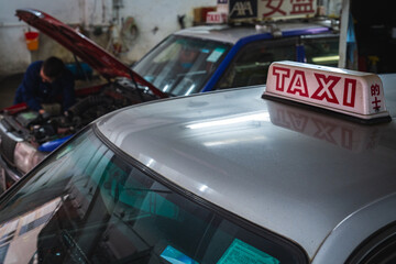 Taxi Sign Close-up With Mechanic Working in Background in garage in in Hong Kong