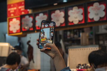 Capturing Michelin Street Food Stall Through Smartphone Screen taking Photo