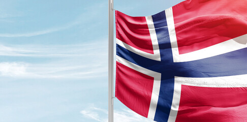 Norway national flag with mast at light blue sky.