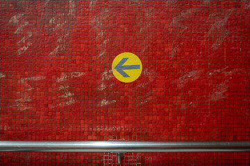 Subway Metro Yellow Arrow Sign on Distressed Red Tile Wall typical Hong Kong