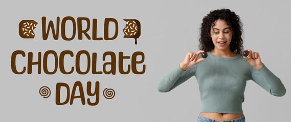 Beautiful young African-American woman with sweet chocolate candies on grey background