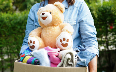 Volunteer collect cloth and doll in cardboard box to donate.