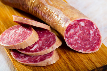 View of smoked salchichon sausage and slices on wooden background